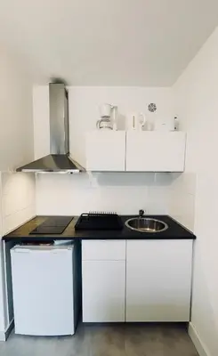a white kitchen with a sink and a counter at Nice Promenade 2 in Nice