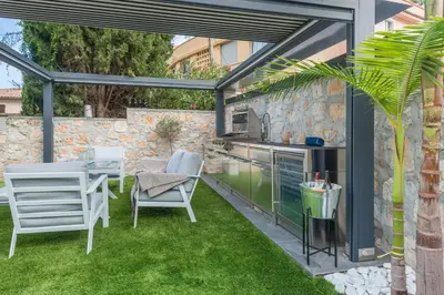an outdoor kitchen and dining area with a pergola at GROUND FLOOR VILLA GRAZIELLA 200 M FROM THE BEACH in Èze