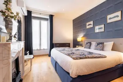 a bedroom with a large bed and a blue wall at From 1882, romantic flat, in the Golden Square in Nice