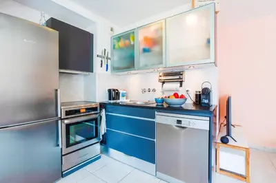 a kitchen with blue cabinets and a stainless steel refrigerator at PALAIS LIBERTE V AP4267 By Riviera Holiday Homes in Nice
