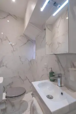 a white bathroom with a sink and a toilet at Studio lumineux à 10 min de la plage in Nice