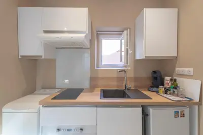 a kitchen with white cabinets and a sink and a window at Studio lumineux à 10 min de la plage in Nice