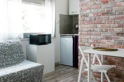 a kitchen with a brick wall and a white table and chair at Apart Nissa Bella Centre / Promenade des Anglais in Nice