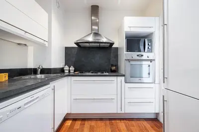 a white kitchen with white cabinets and a sink at Extraordinary Sea View - 1 Bdr with AC in Villefranche-sur-Mer