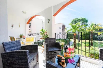 a balcony with wicker chairs and a table with flowers on it at L'ANGE GARDIEN AP4269 by Riviera Holiday Homes in Villefranche-sur-Mer