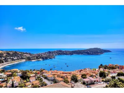 an aerial view of a town and a beach with boats at L'ANGE GARDIEN AP4269 by Riviera Holiday Homes in Villefranche-sur-Mer