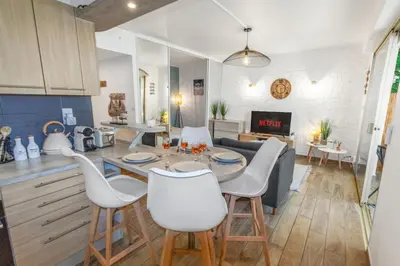 a kitchen and living room with a table and chairs at Le Pied Dans L'eau - Parking - Seaside - Hipprodrome in Cagnes-sur-Mer