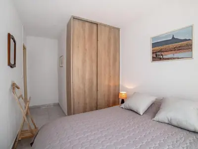 a bedroom with a bed and a wooden closet at Apartment Le Giono by Interhome in Saint-Laurent-du-Var