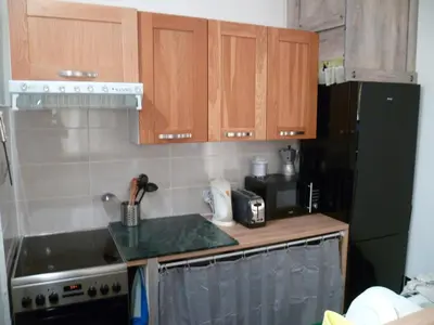 a kitchen with wooden cabinets and a black refrigerator at Joli 3 pièces, 7 pers, très lumineux, Nice centre in Nice