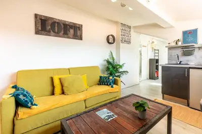 a living room with a yellow couch and a table at Homelivia, ATTIC ROOM -Mansardé sous les toits de Nice in Nice