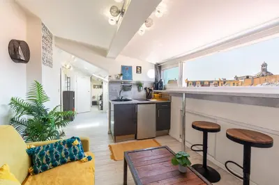 a living room with a yellow couch and a kitchen at Homelivia, ATTIC ROOM -Mansardé sous les toits de Nice in Nice