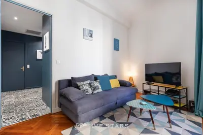 a living room with a couch and a tv at Suite Alsace Lorraine FSHH in Nice