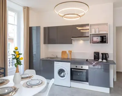 a kitchen with a washing machine and a table with chairs at Lovely apartment with terrace Nice centre in Nice