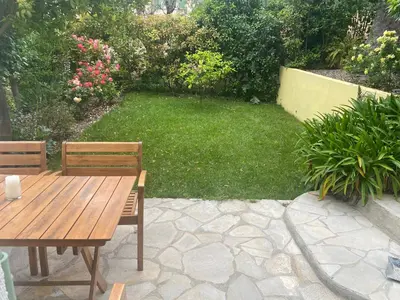 a wooden table and two chairs in a garden at Appt avec jardin et clim proche Arènes de Cimiez in Nice