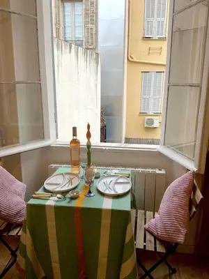 a table with a green and yellow table cloth and a window at AM STUDIO NICE in Nice