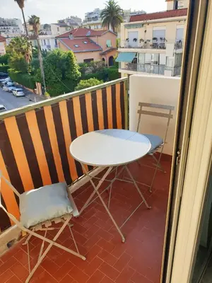 a table and chair on a balcony with a view of a city at Beautiful T1 with sea view in Nice