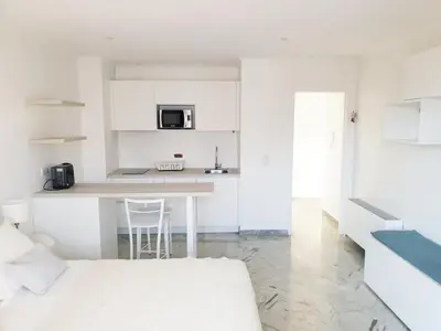 a white kitchen with a counter and a table at Beautiful T1 with sea view in Nice