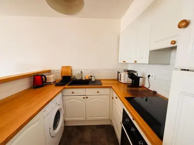 a kitchen with white cabinets and a washer and dryer at Plage Landsberg - Saint-Laurent-du-Var in Saint-Laurent-du-Var