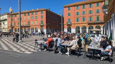 a group of people sitting at tables in a street at Stunning Duplex place Masséna 2 mins walk from beaches in Nice