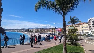 a group of people walking on a sidewalk near the beach at Stunning Duplex place Masséna 2 mins walk from beaches in Nice
