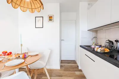 a kitchen with a wooden table and white cabinets at L'ANGE GARDIEN III AP4293 By Riviera Holiday Homes in Villefranche-sur-Mer