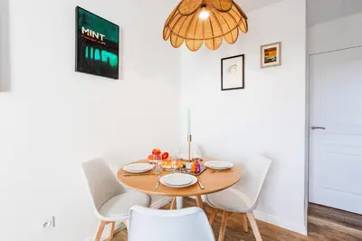 a dining room with a wooden table and white chairs at L'ANGE GARDIEN III AP4293 By Riviera Holiday Homes in Villefranche-sur-Mer