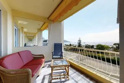 a porch with a couch and a chair on a balcony at Suite Horizon FSHH in Beaulieu-sur-Mer
