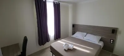 a bedroom with a bed with a wooden headboard and a window at ESPERANCE HOTEL in Nice