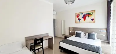 a bedroom with two beds and a desk and a painting at ESPERANCE HOTEL in Nice