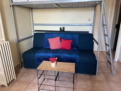 a blue couch with two red pillows and a table at 
