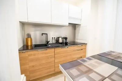 a kitchen with wooden cabinets and a counter top at Новая 3-комнатная квартира на 2й линии от моря. in Nice