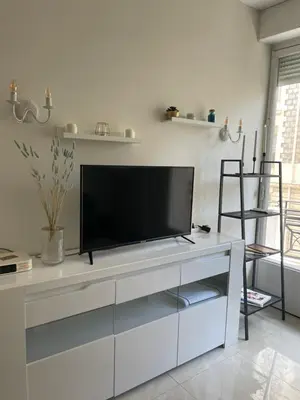 a living room with a flat screen tv on a white cabinet at Новая 3-комнатная квартира на 2й линии от моря. in Nice