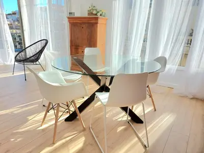 a glass dining table and chairs in a room with windows at Le Metropole Nice Victor Hugo in Nice