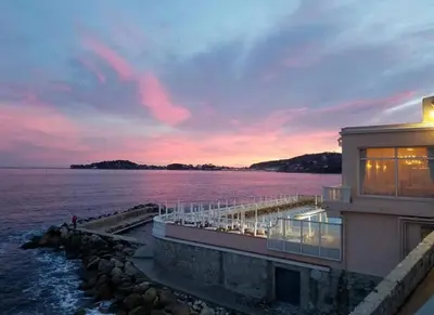 a building with a view of the water at sunset at Stunning Beaulieu Sur mer Retreat Chic with Air-Conditioning and Breathtaking Views in Beaulieu-sur-Mer