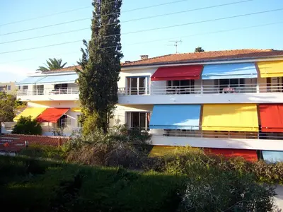 a building with a rainbow facade with a palm tree at Le Val Duchesse Hotel & Appartements in Cagnes-sur-Mer