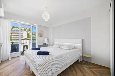 a white bedroom with a bed and a large window at Le Hammam Azur in Nice
