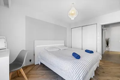 a white bedroom with a bed and a chair at Le Hammam Azur in Nice