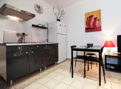 a kitchen with a black table and a table and a refrigerator at PV STUDIO Five Stars Holiday House in Nice