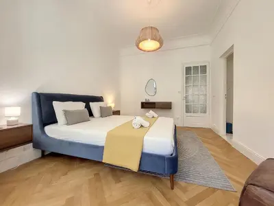 a bedroom with a large bed with a blue chair at Nestor&Jeeves - STANDING BAQUIS - Central - Close sea in Nice