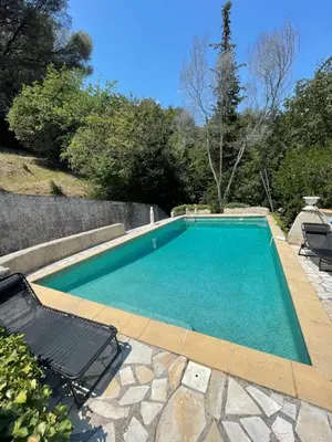 a swimming pool with two lounge chairs next to it at Studio en bas de villa avec piscine proche bord de mer in Cagnes-sur-Mer