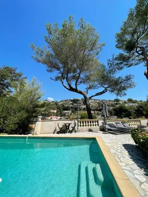 a swimming pool with a tree in the background at Studio en bas de villa avec piscine proche bord de mer in Cagnes-sur-Mer