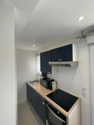 a small kitchen with black cabinets and a stove at Studio en bas de villa avec piscine proche bord de mer in Cagnes-sur-Mer
