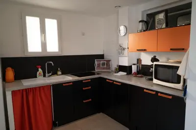 a kitchen with black and orange cabinets and a microwave at Perle in Nice
