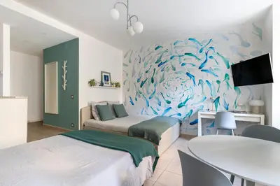 a living room with two beds and a table and a painting at AZUR Apartment - Quiet City Center Location by the Sea in Nice