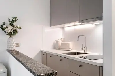a white kitchen with a sink and a vase of flowers at AZUR Apartment - Quiet City Center Location by the Sea in Nice