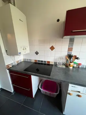 a kitchen with a black counter top and red cabinets at 2 pièces avec terrasse en résidence privée in Nice