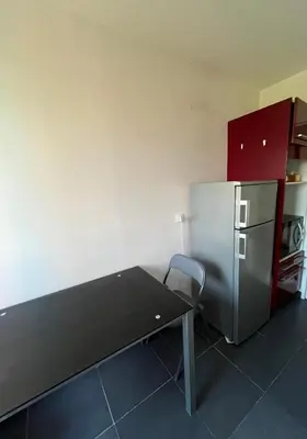 a kitchen with a table and a refrigerator at 2 pièces avec terrasse en résidence privée in Nice