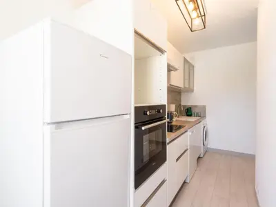 a kitchen with white cabinets and a refrigerator at Apartment Les Trois Caps by Interhome in Cagnes-sur-Mer