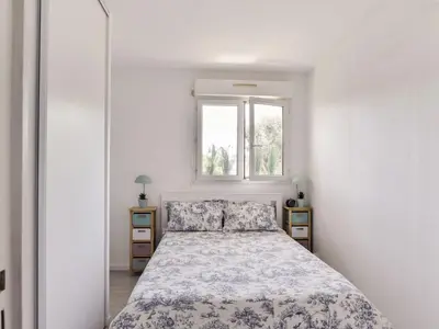 a white bedroom with a bed and a window at Apartment Cimiez Les Pins by Interhome in Nice