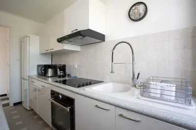 a white kitchen with a sink and a counter top at Apartment T2 air-conditioned sea view in Saint-Laurent-du-Var